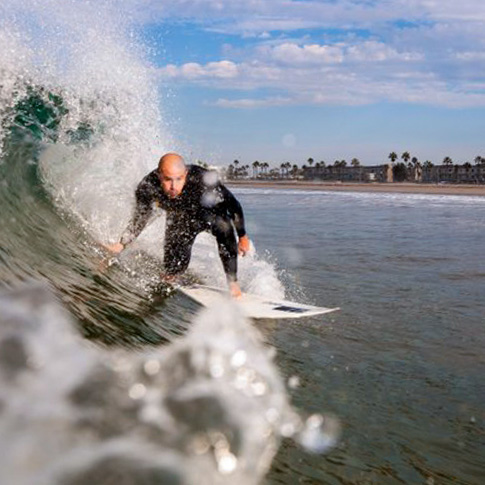 Surfer at hueneme beach park surfing a clean walled wave. Surfing makes Port Hueneme an attractive affordable beach vacation option.